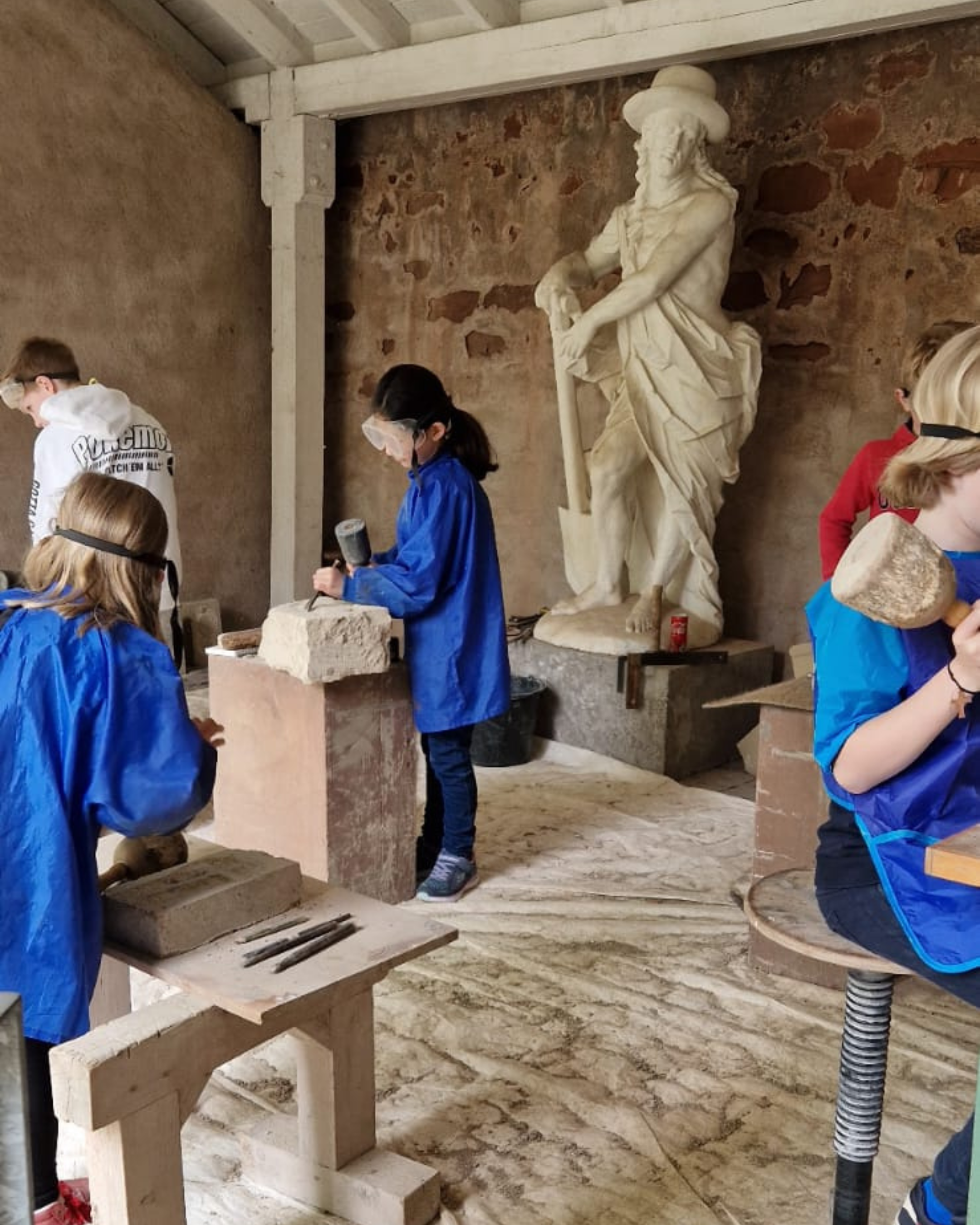 Kinder machen einen Steinmetz-Workshop und arbeiten mir Werkzeugen an Steinen.