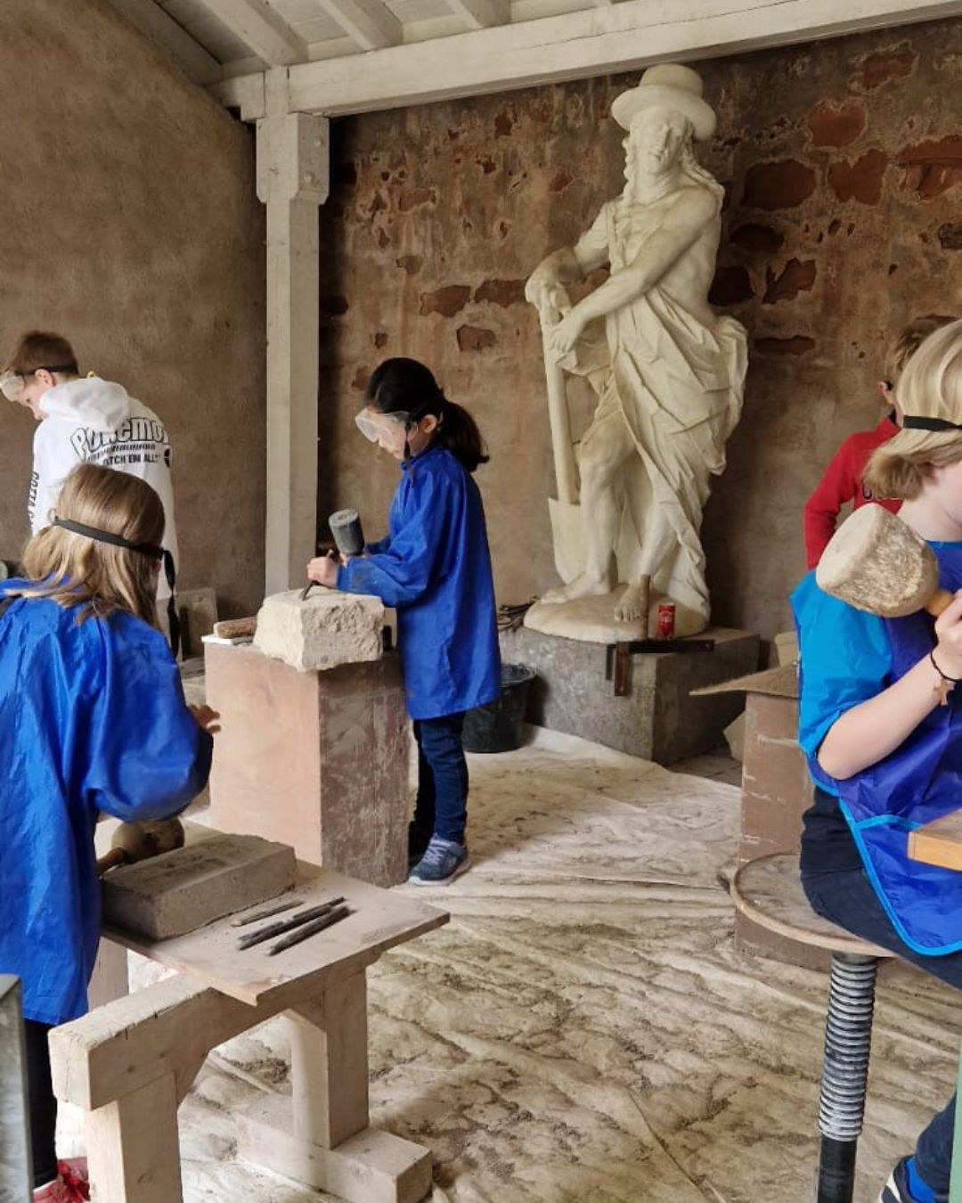 Dombauhütte - Oster-Ferienprogramm (c) Museum am Dom Kinder machen einen Steinmetz-Workshop und arbeiten mir Werkzeugen an Steinen.