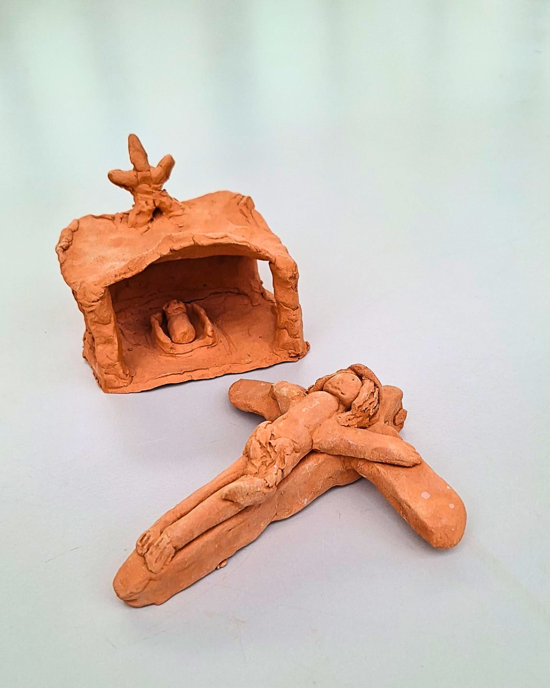 Krippe und Kreuz, von Kindern aus Ton getöpfert